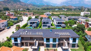 A residential area with modern houses, a clear road, and mountains in the background. - Sweet Home Kemer Apartments (Kemer)