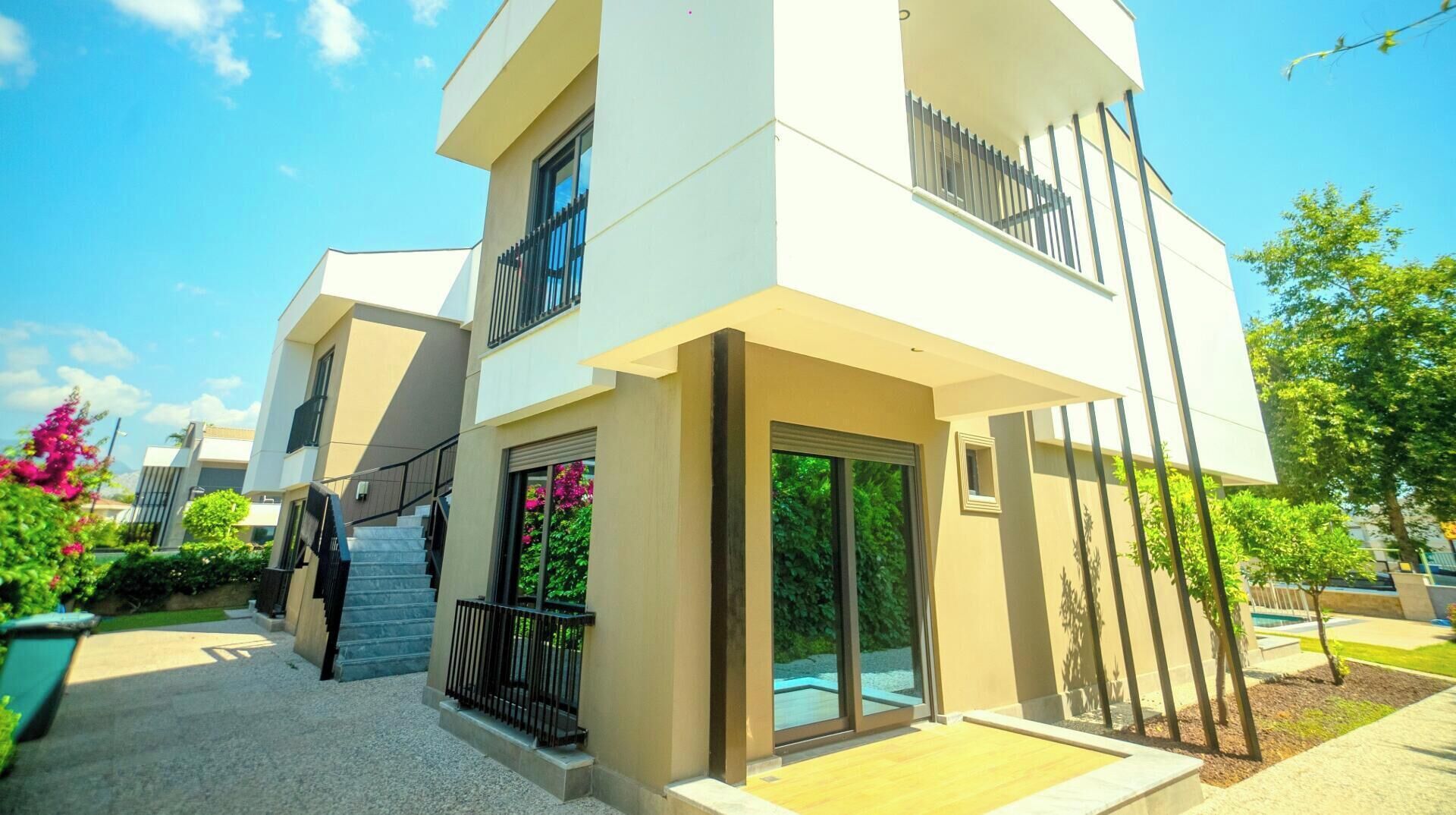 A multi-story residential building with a staircase leading to the entrance, a balcony, and a glass door.