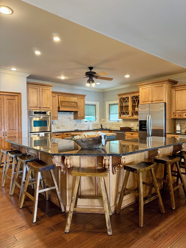 A modern kitchen with wooden cabinets, stainless steel appliances, and a central island with bar stools.