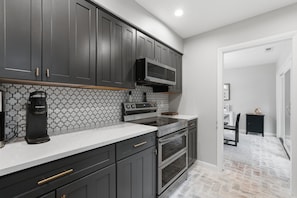 Una cocina con armarios oscuros, microondas, cafetera y salpicadero de azulejos.