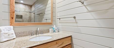 A bathroom with a wooden vanity, a sink, a mirror, and a towel rack.
