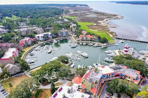 Un port de plaisance où sont amarrés des bateaux, entouré de bâtiments résidentiels et d’un terrain de golf.