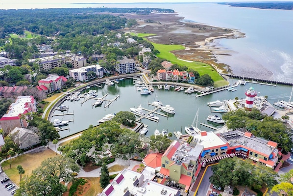 A marina with boats docked, surrounded by residential buildings and a golf course.