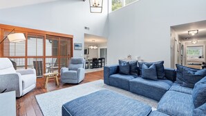 Un salón amplio con un sofá grande, un sillón más pequeño y una mesa de comedor.