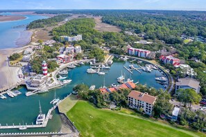 An aerial view of a marina with boats, a lighthouse, and surrounding buildings.