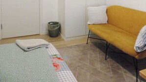 A bedroom with a bed, a wardrobe, a sofa, and a trash bin. - Close to nørreport 206 (København)