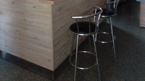 Een houten bar met krukken, een aanrecht en diverse keukenbenodigdheden.