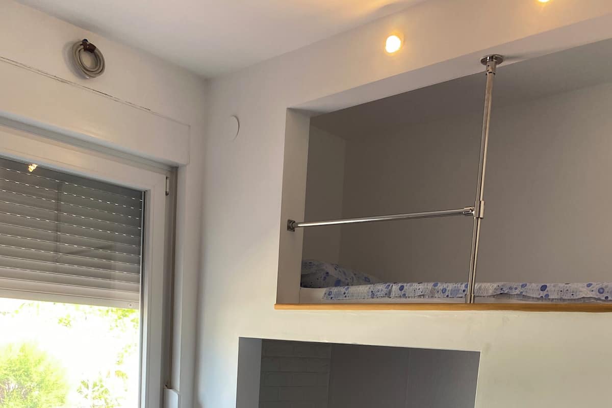 A bunk bed room with a window, a radiator, and a ladder.