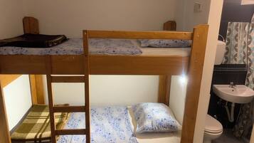 Dormitorio con literas, un lavamanos y un inodoro.