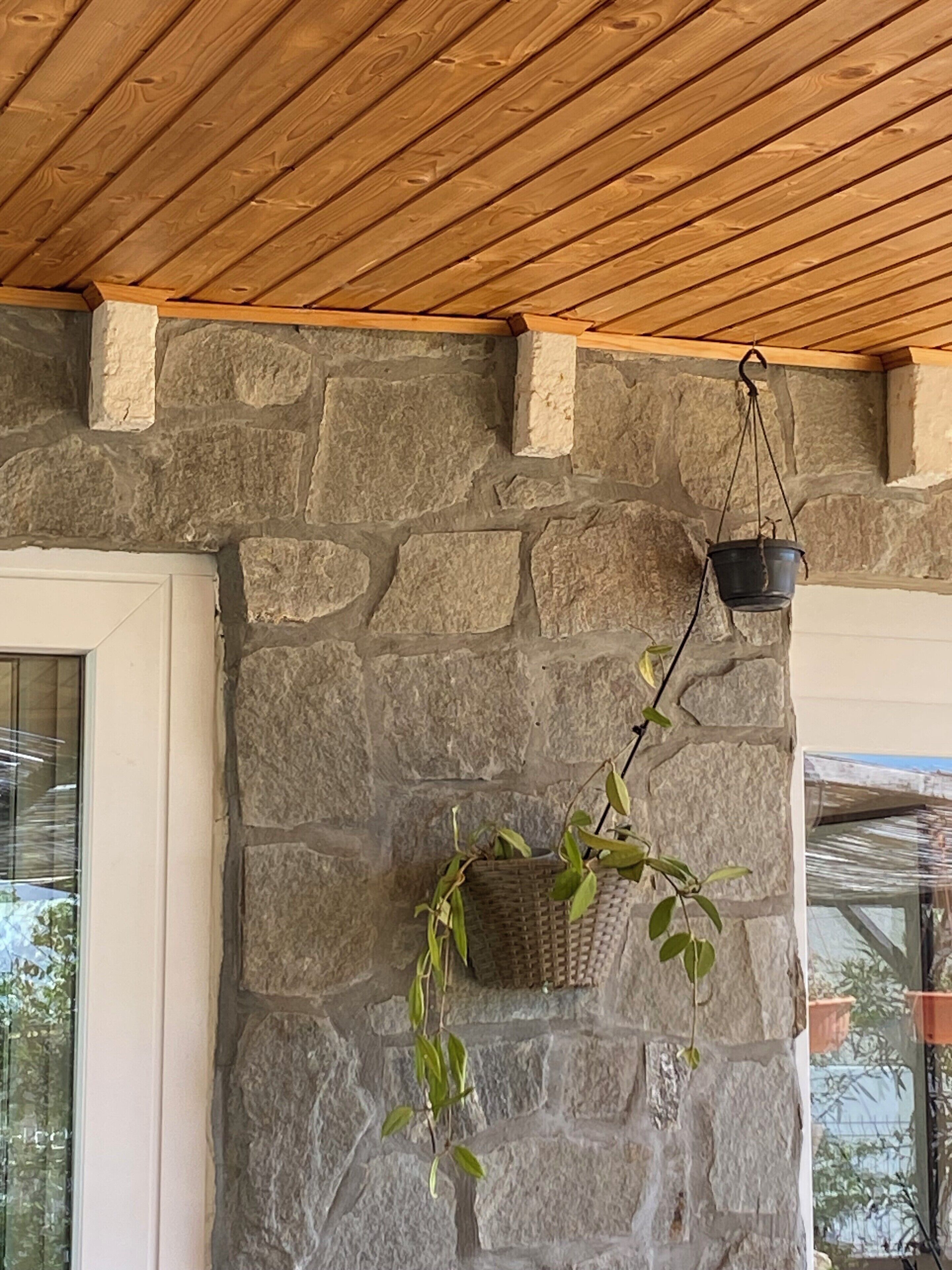 A stone wall with a hanging planter and a window.