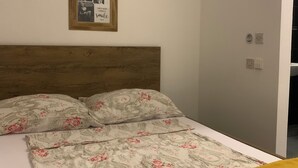 Een slaapkamer met een houten hoofdbord, een bed met bloemenbeddels en een ingelijst schilderij aan de muur.