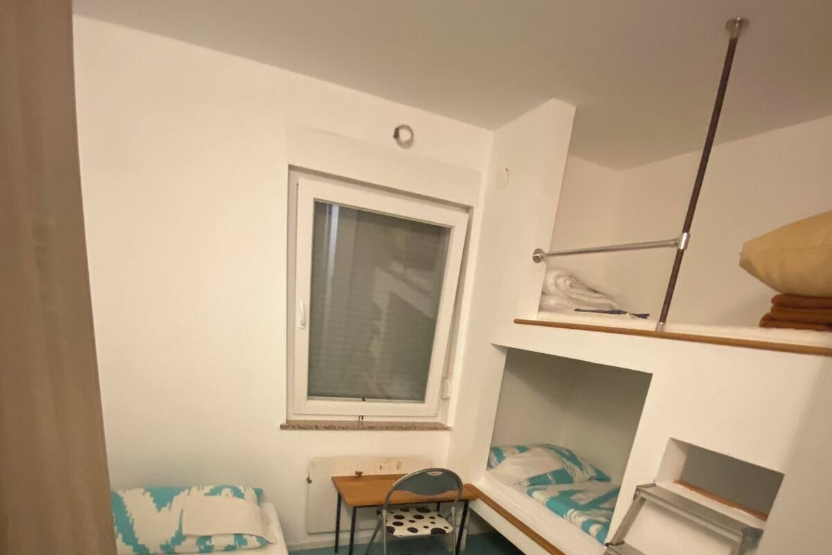 A small, compact room with bunk beds, a desk, and a chair.