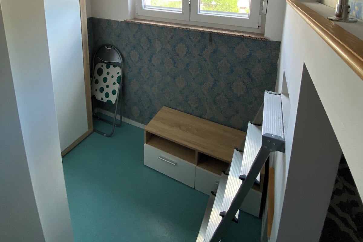 A small, compact room with a window, a bench, and a radiator.