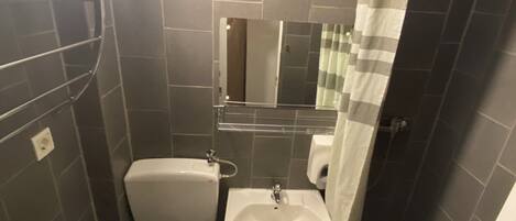 Un baño pequeño y funcional con inodoro, lavabo y zona de ducha.