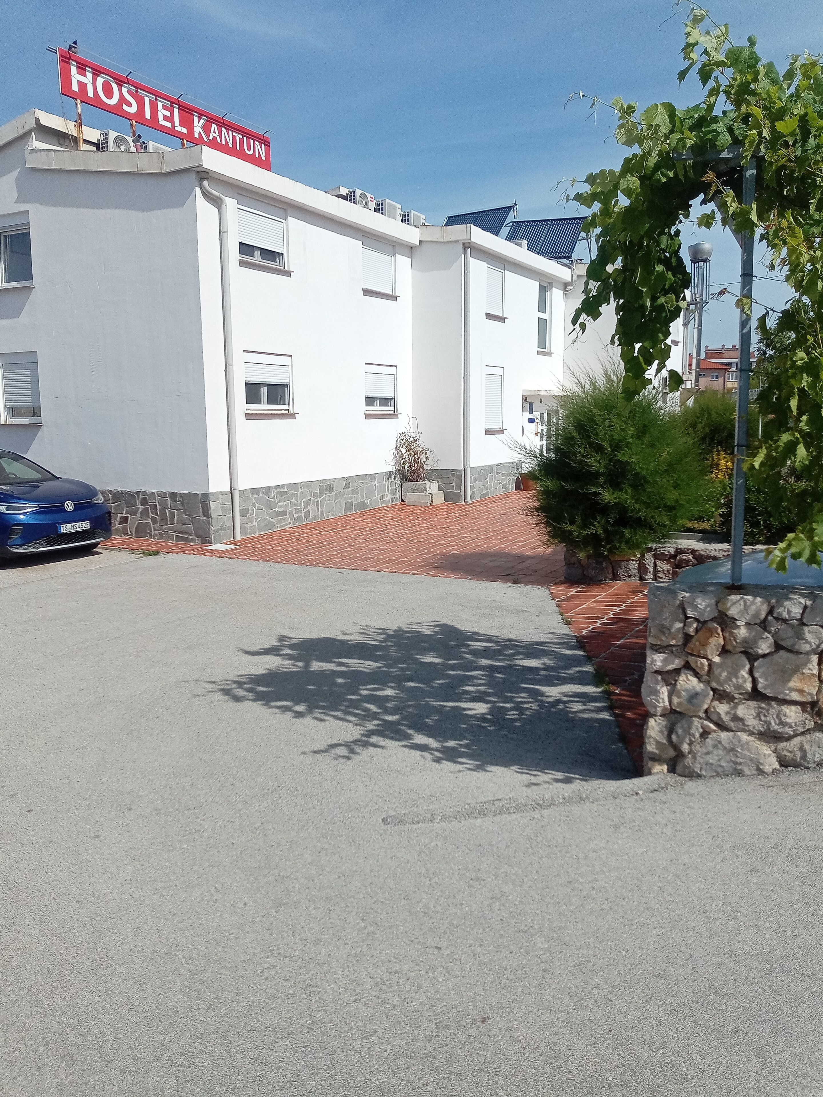 Un bâtiment sur lequel on peut lire l’inscription « AUBERGE KANTUN », avec une voiture bleue garée devant.