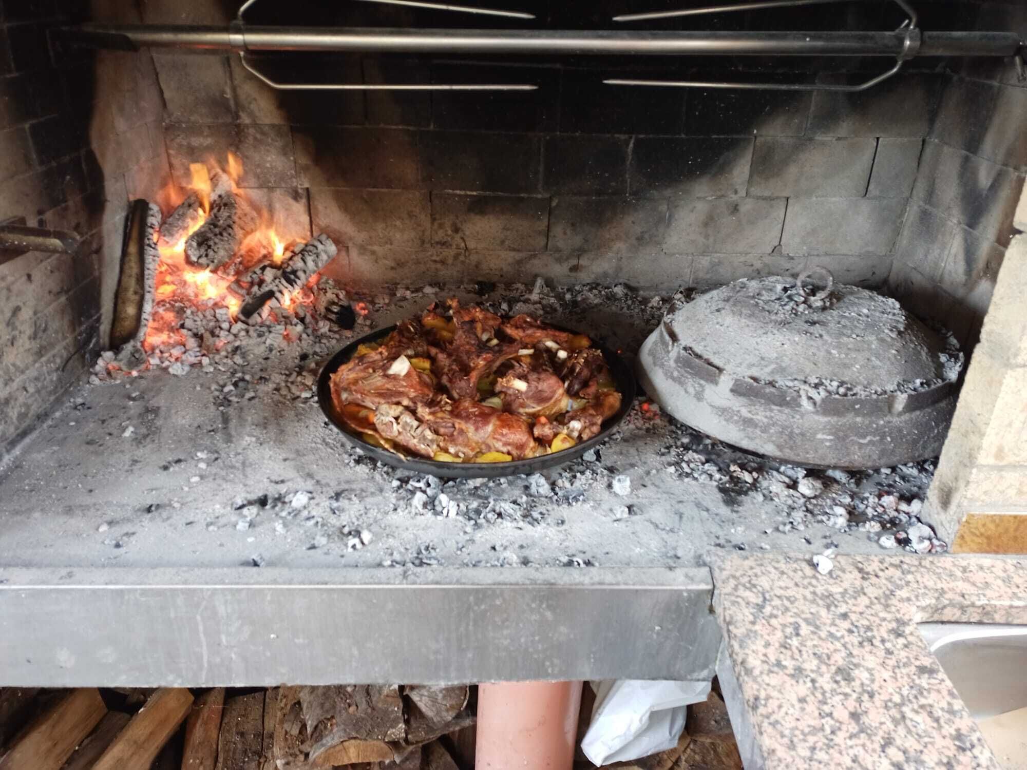 Un forno a legna tradizionale con una teglia di carne che cuoce all'interno.