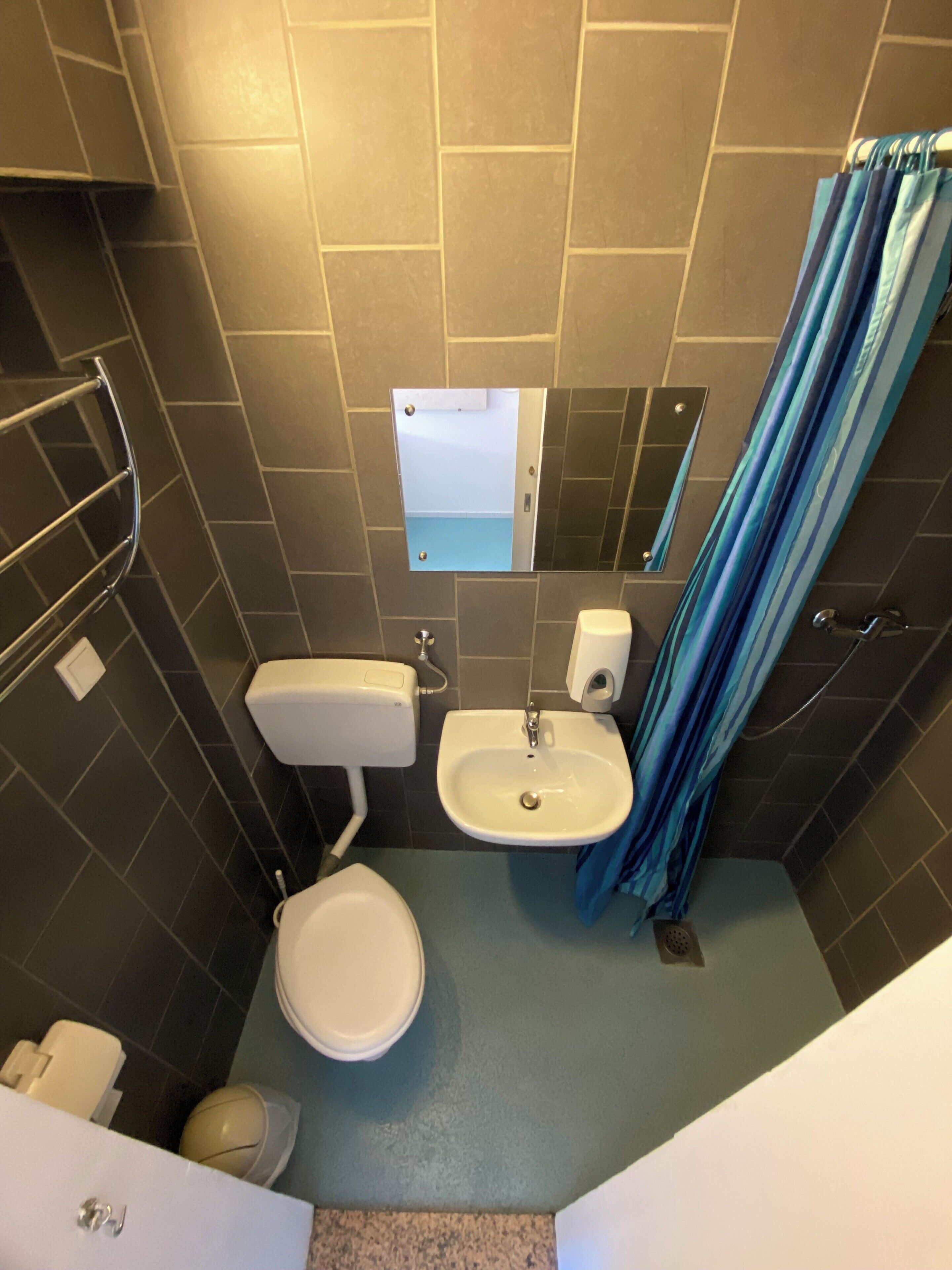 A compact bathroom with a toilet, sink, and mirror.