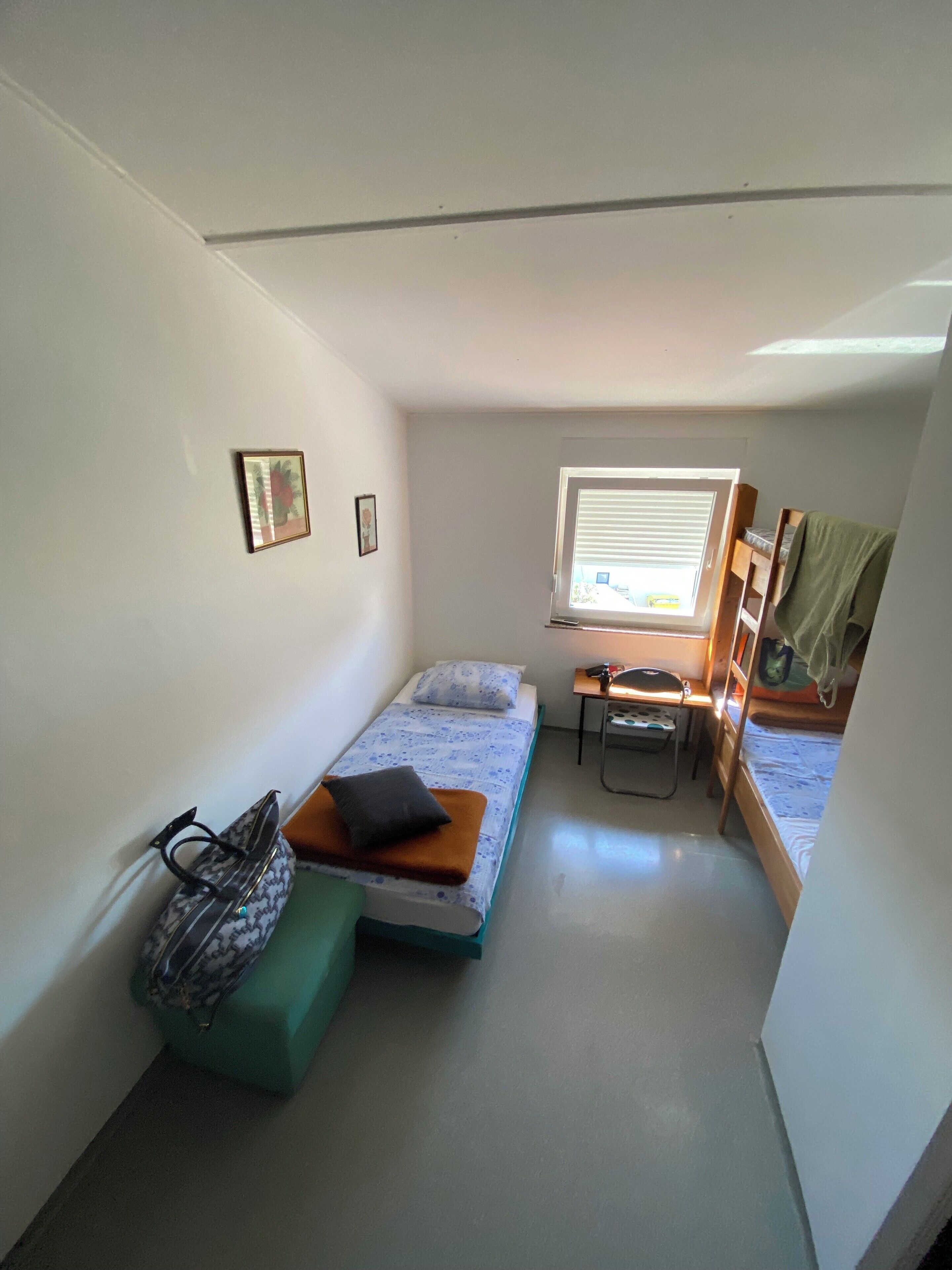 A small, compact room with a bunk bed, a desk, and a window.