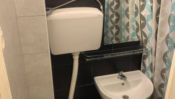 A small bathroom with a toilet, sink, and shower curtain.