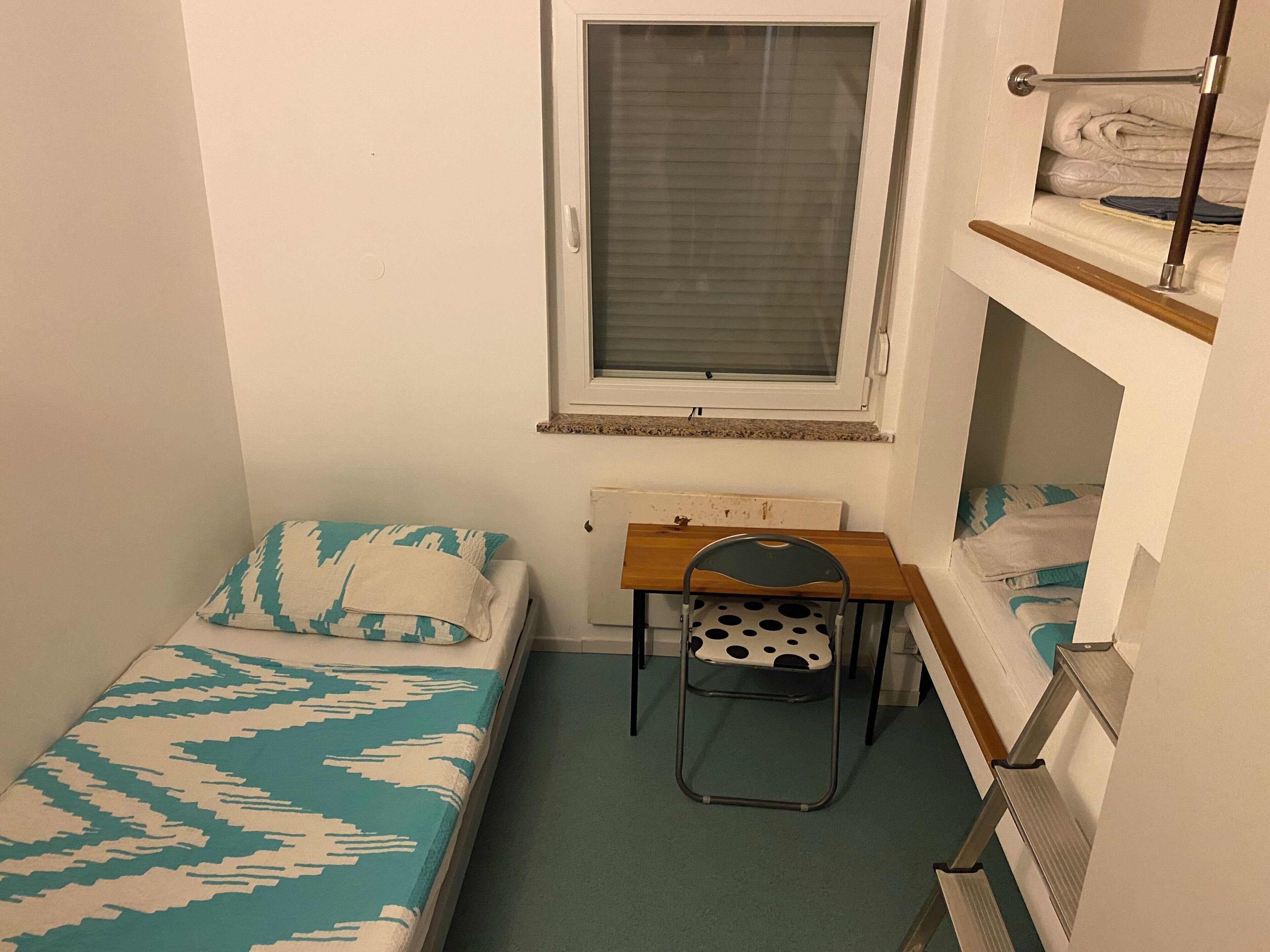 A small, compact room with a bunk bed, a desk, and a chair.