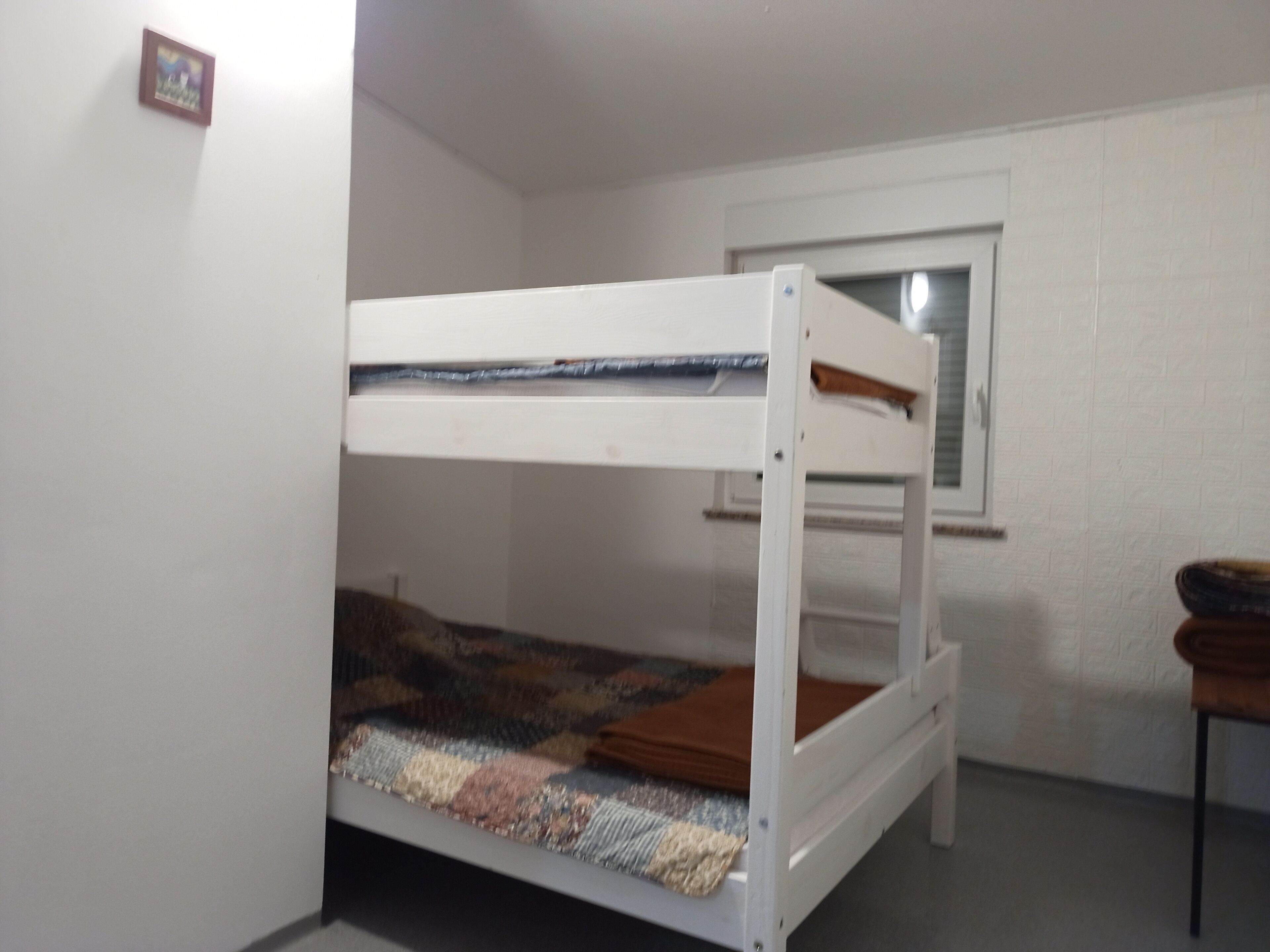 A bunk bed in a room with white walls and a window.
