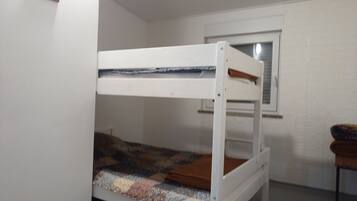 A bunk bed in a room with white walls and a window.