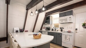 Una cocina con una isla blanca, armarios grises y un refrigerador blanco.