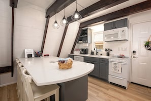 A kitchen with a white island, grey cabinets, and a white refrigerator.