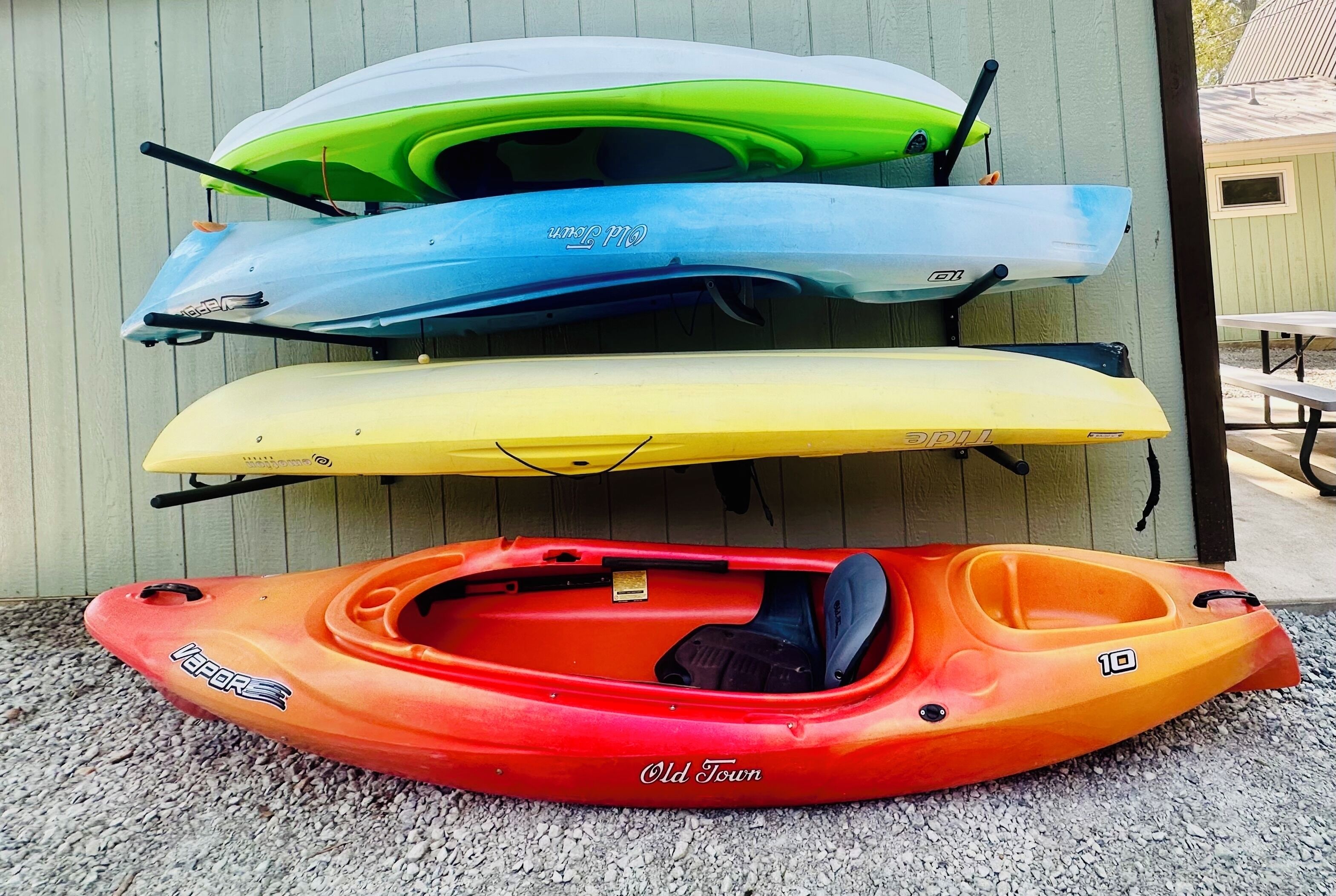 Kayaks of various colors and designs, including a red kayak labeled "Old Town" and others in green, blue, and yellow.