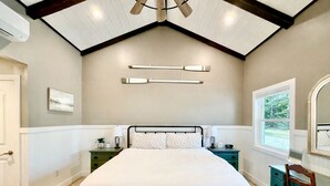 Un dormitorio con cama, mesitas de noche, ventana y ventilador de techo.