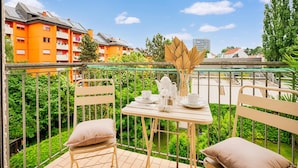 A balcony with a table set for tea, chairs, and a view of orange buildings. - Arcadio Home - Premium Suite (Graz)