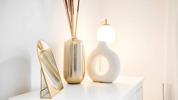 A white table with a decorative glass object and a vase with reeds.