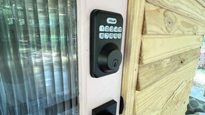 Cerradura electrónica con teclado en una puerta de madera con ventana y picaporte negro.