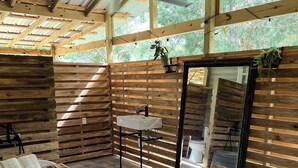 Interior rústico de una cabaña con una bañera grande, paredes de madera, una mesita y un espejo.
