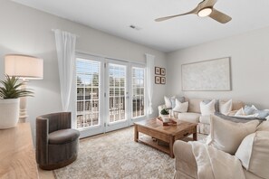 A living room with a sofa, armchair, coffee table, and a ceiling fan.