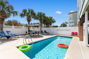 A swimming pool with lounge chairs and palm trees.