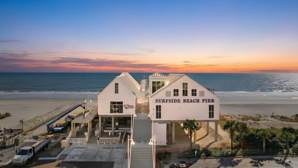 A building labeled 'Surfside Beach Pier' with a staircase leading to the entrance, situated on a beach with the ocean in the background. - Retreat w/ Private Pool & Ocean View in Surfside Beach (Surfside Beach)