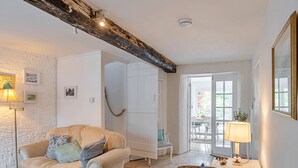 Un soggiorno accogliente con una parete in mattoni bianchi, un trave in legno al soffitto, un divano beige e un divano marrone, oltre a un armadietto bianco.