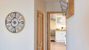 A hallway with a wooden door leading to a kitchen area. - Sea Bank (Colwyn Bay)