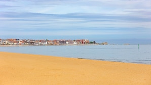 A beach with a row of buildings in the background. - Sea Bank (Colwyn Bay)