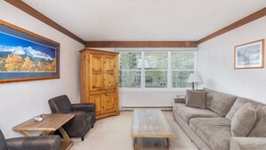 A living room with a wooden cabinet, a sofa, a coffee table, and two armchairs. - Mountainside Inn 413 1 Bedroom Condo (Telluride)