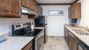 A kitchen with wooden cabinets, a stainless steel stove, a refrigerator, and a microwave. - Mountainside Inn 413 1 Bedroom Condo (Telluride)