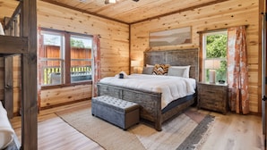 A wooden cabin bedroom with a bed, bench, and ceiling fan. - Splash Mountain Lodge 8 Bedroom Cabin (Sevierville)