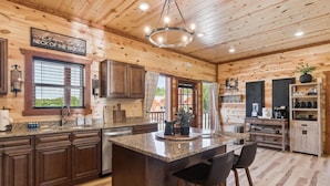 A spacious kitchen with wooden cabinetry, a granite countertop, and a central island with bar stools. - Splash Mountain Lodge 8 Bedroom Cabin (Sevierville)