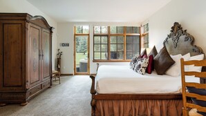 Een slaapkamer met een groot bed, een houten hoofdeinde en uitzicht op een jacuzzi door een groot raam.