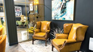 Un interior moderno con dos sillones de cuero, un cuadro abstracto grande y un panel decorativo en la pared.