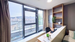Una habitación moderna con un ventanal grande, un escritorio, una silla, una cama y una estantería.