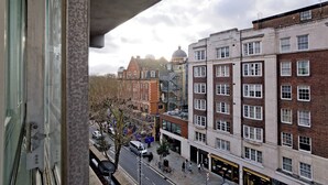 A view from a window overlooking a street with buildings, including a mix of residential and commercial structures. - Imperial Queensway Apartment (London)