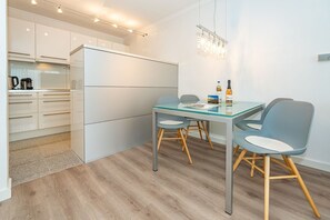 A modern kitchen with white cabinets, a glass dining table, and two chairs. - Lieblingsplatz - Comfortable vacation apartment Lieblingsplatz with balcony and (Sylt)