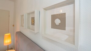 Ein Flur mit gerahmten Kunstwerken an der Wand, einer Lampe und einer Bank.